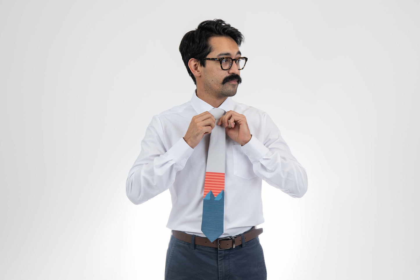 A man wearing a light gray and blue mountain tie with orange and pink stripes. Formal tie from Kator Shop Logan — refined Utah design for galas, ceremonies, and special occasions.