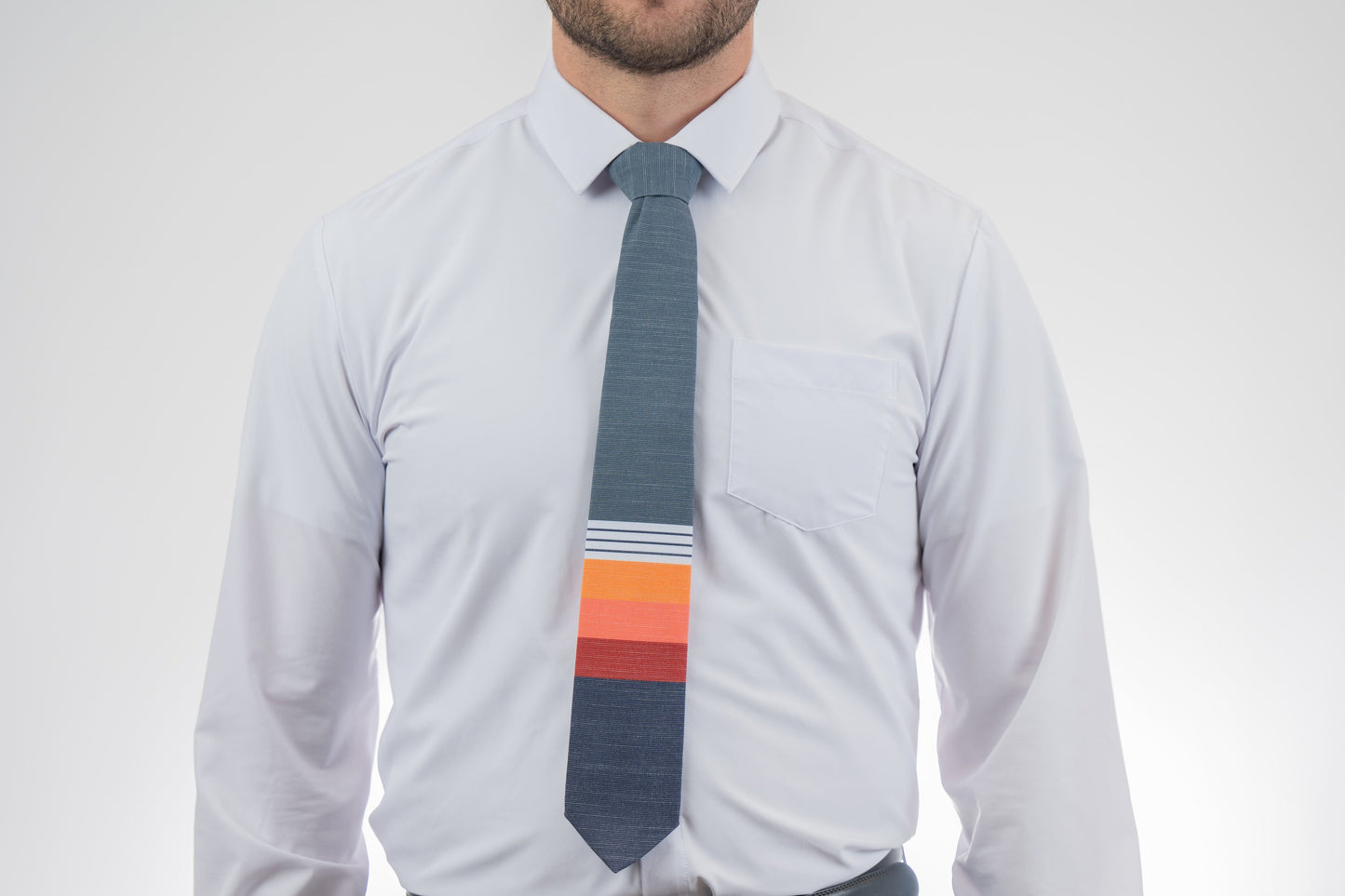 Man wearing a modern, cool necktie with thick, color blocked stripes of yellow, peach, and red