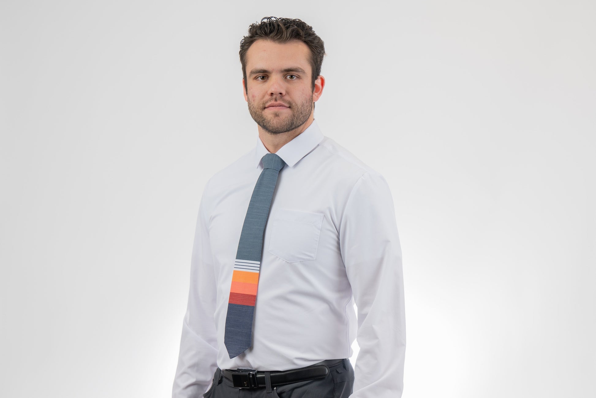 Man wearing a modern, colorful, cool necktie with thick, color blocked stripes of yellow, peach, and red