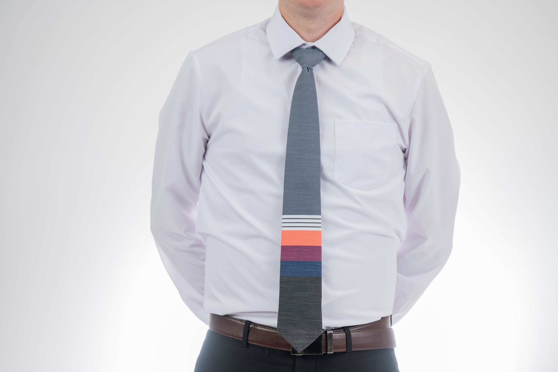 A man wearing a cool, modern necktie with thick coral, purple, and blue stripes