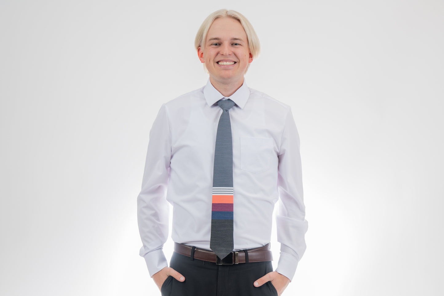 A man wearing a cool, modern necktie with thick coral, purple, and blue stripes