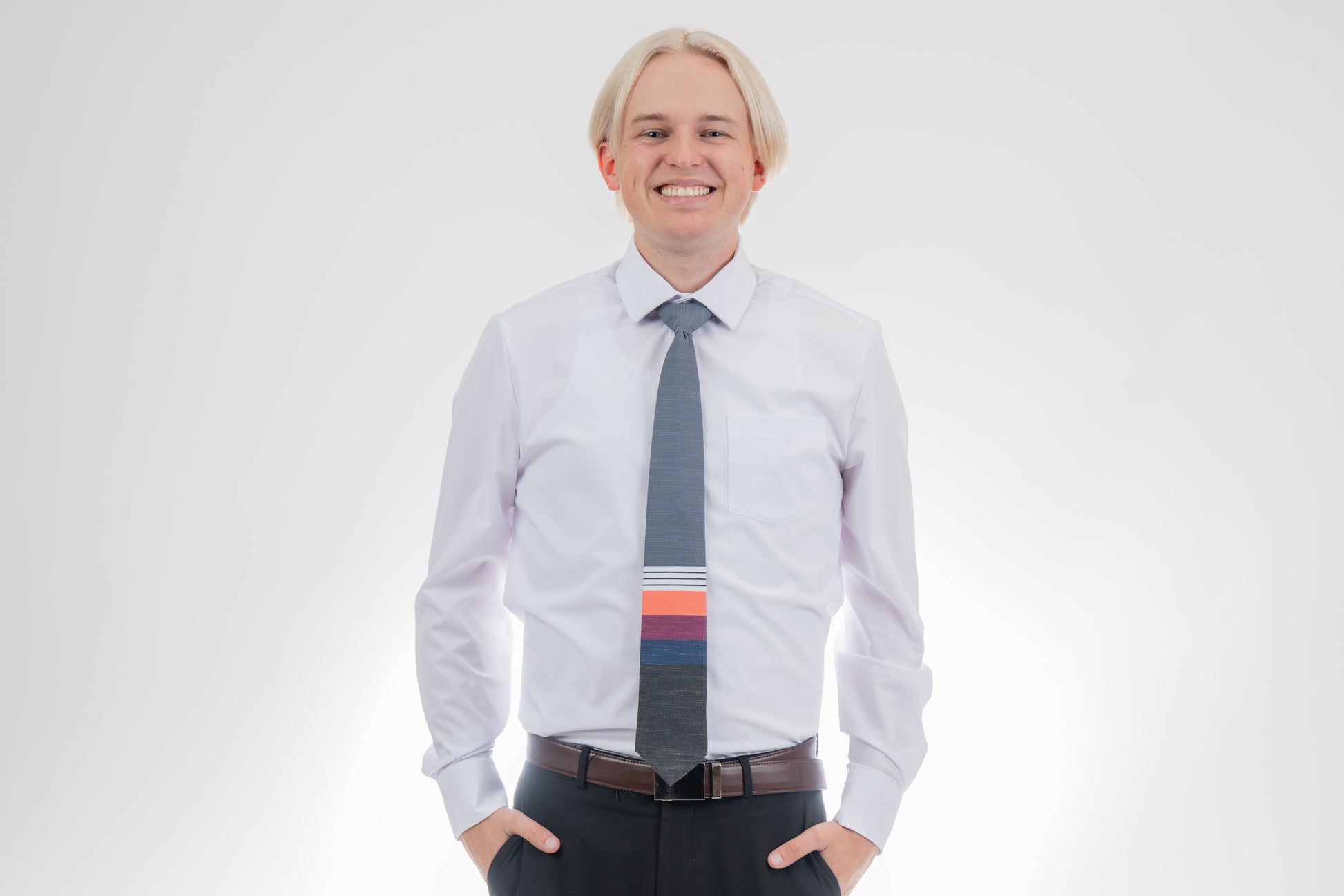 A man wearing a cool, modern necktie with thick coral, purple, and blue stripes