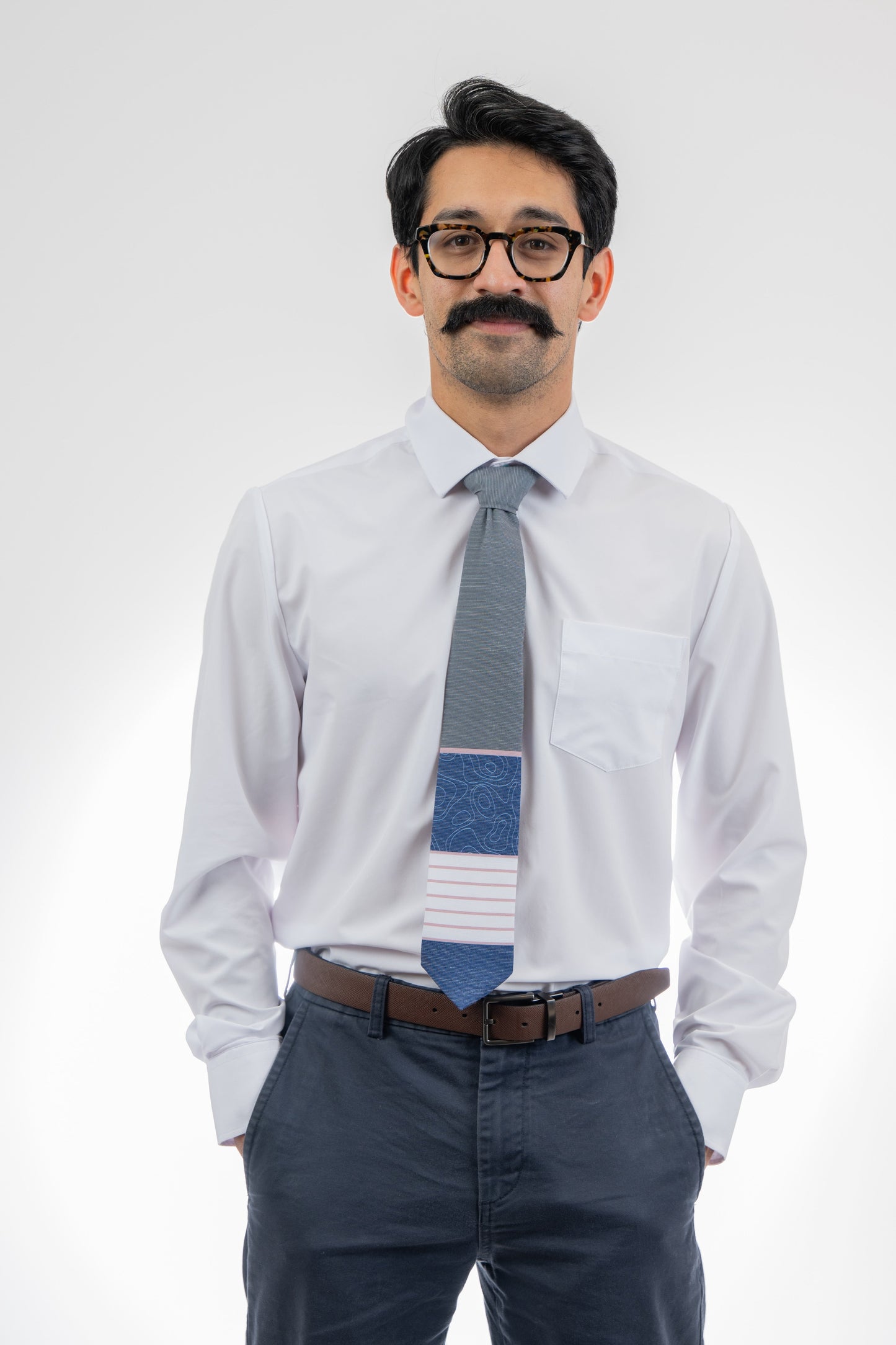 A man wearing a gray, pink, and blue necktie with stripes and topography lines  Tie crafted for durability and class – Kator Shop Logan’s signature accessory for modern Utah men.